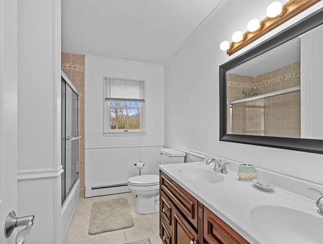 bathroom with toilet, double vanity, baseboard heating, and a sink