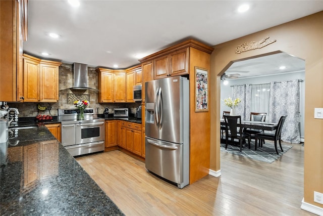 kitchen featuring sink, light hardwood / wood-style flooring, wall chimney range hood, and appliances with stainless steel finishes