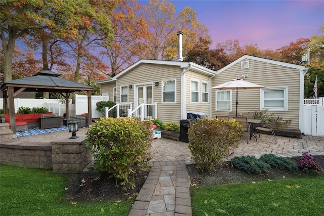 back house at dusk featuring a gazebo, an outdoor living space, and a patio area