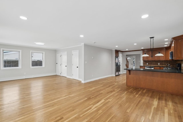 kitchen with decorative light fixtures, light hardwood / wood-style flooring, appliances with stainless steel finishes, kitchen peninsula, and decorative backsplash