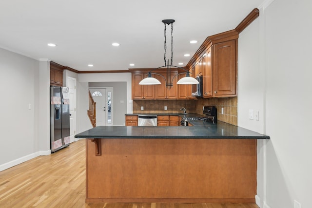 kitchen featuring tasteful backsplash, decorative light fixtures, light hardwood / wood-style flooring, kitchen peninsula, and stainless steel appliances