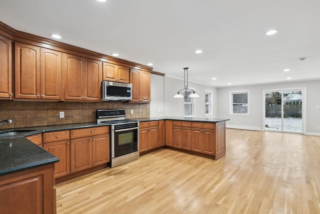 kitchen featuring sink, range with gas cooktop, tasteful backsplash, decorative light fixtures, and light hardwood / wood-style floors