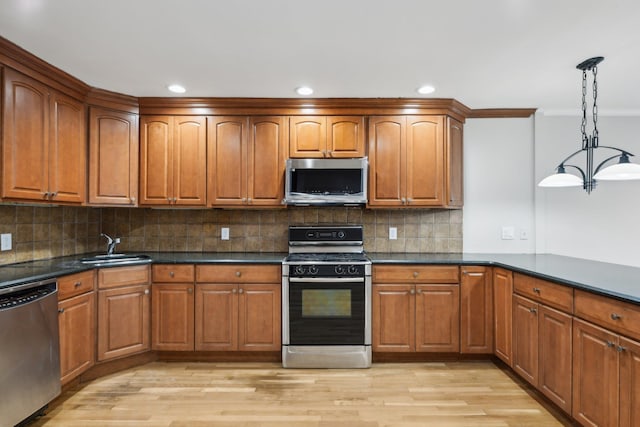 kitchen featuring hanging light fixtures, appliances with stainless steel finishes, sink, and light wood-type flooring