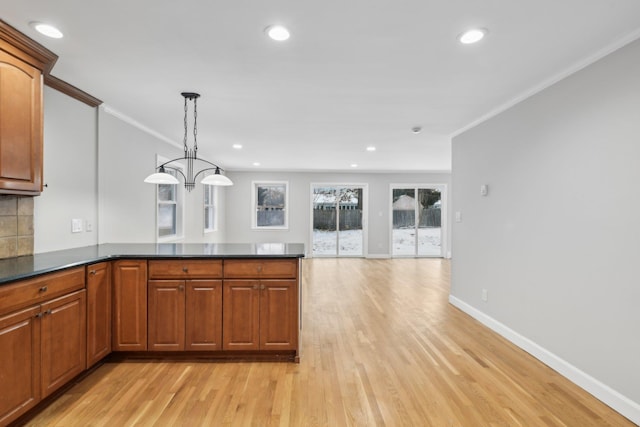 kitchen featuring crown molding, decorative light fixtures, light hardwood / wood-style floors, and backsplash