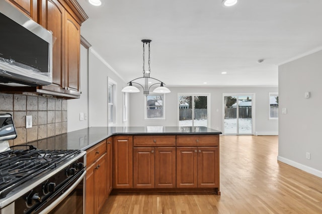 kitchen with crown molding, hanging light fixtures, range with gas stovetop, light hardwood / wood-style floors, and kitchen peninsula