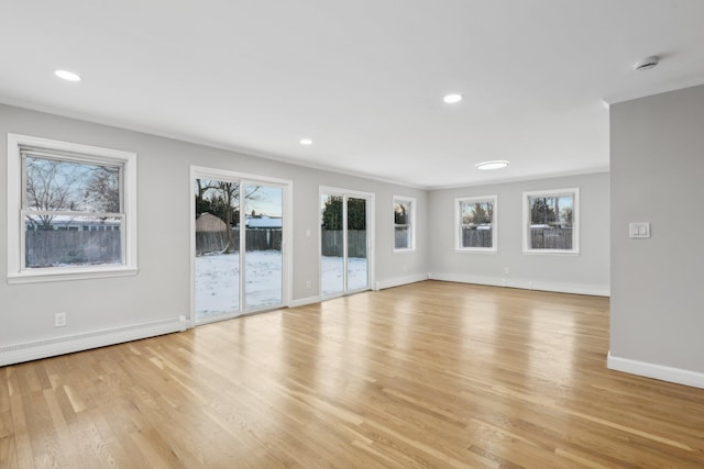 unfurnished living room with baseboard heating, ornamental molding, and light wood-type flooring