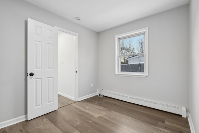 empty room featuring hardwood / wood-style flooring and baseboard heating