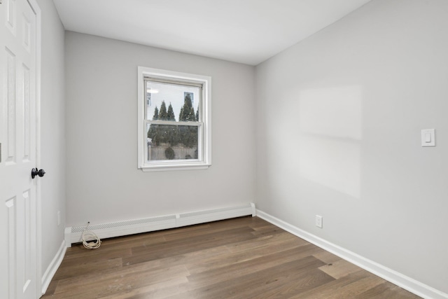 spare room with a baseboard heating unit and dark hardwood / wood-style floors