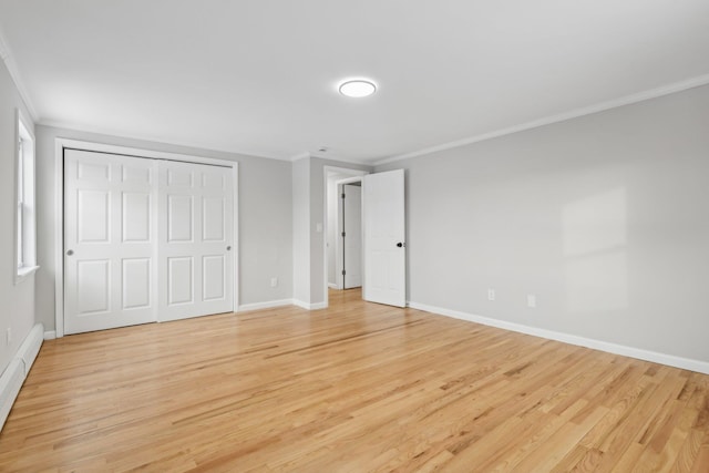 unfurnished bedroom with baseboard heating, ornamental molding, a closet, and light wood-type flooring