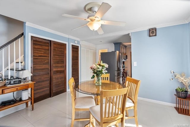 tiled dining space featuring ceiling fan and ornamental molding