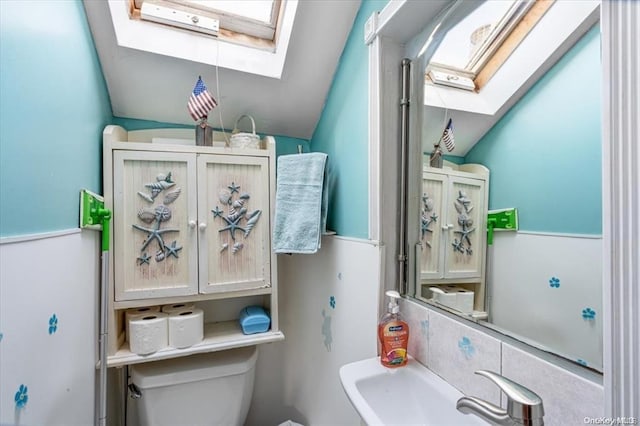 bathroom featuring toilet, lofted ceiling with skylight, and sink