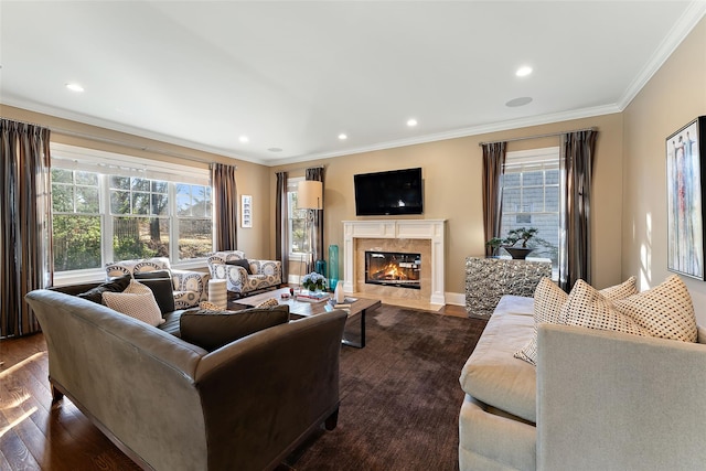 living room with a premium fireplace, dark wood-type flooring, ornamental molding, and a healthy amount of sunlight