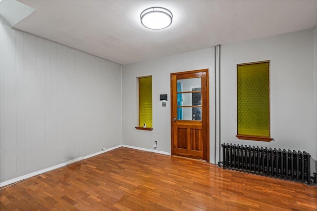 unfurnished room featuring hardwood / wood-style floors and radiator heating unit