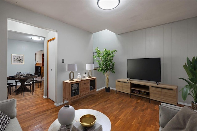 living room with dark hardwood / wood-style floors and wood walls