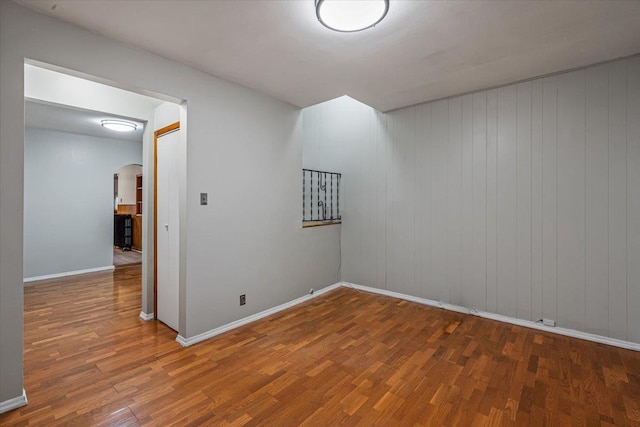 unfurnished room with dark hardwood / wood-style floors and wooden walls