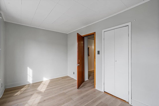 unfurnished bedroom featuring a closet, light hardwood / wood-style floors, and ornamental molding