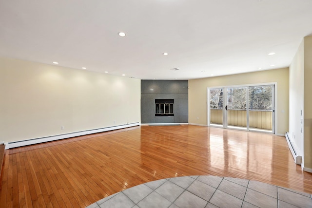 unfurnished living room with a fireplace, light hardwood / wood-style floors, and a baseboard heating unit