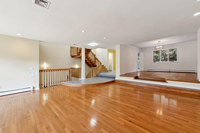 empty room with a baseboard radiator, a notable chandelier, and light wood-type flooring