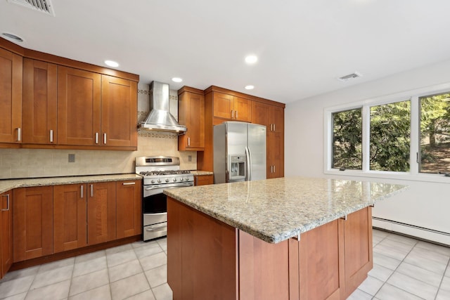 kitchen featuring decorative backsplash, light stone counters, stainless steel appliances, wall chimney range hood, and a kitchen island