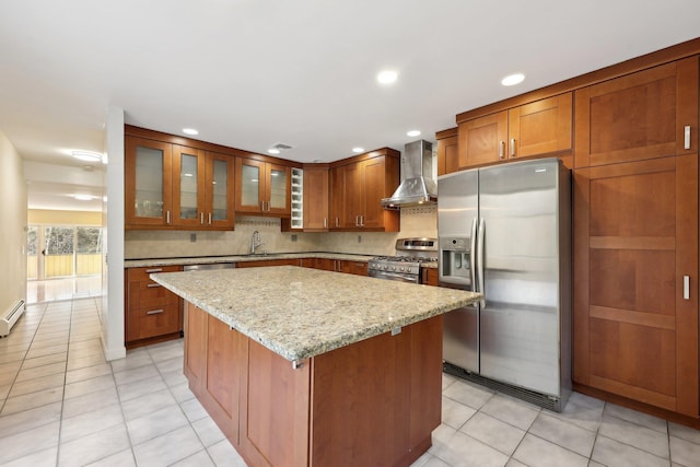 kitchen with appliances with stainless steel finishes, light stone counters, sink, wall chimney range hood, and a kitchen island