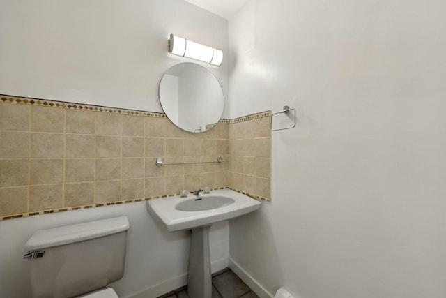 bathroom featuring tile patterned floors, toilet, and tile walls