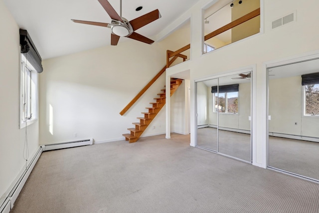 interior space with light carpet, a healthy amount of sunlight, ceiling fan, and a baseboard heating unit