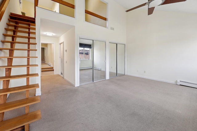 interior space featuring light carpet, a baseboard heating unit, ceiling fan, a towering ceiling, and multiple closets