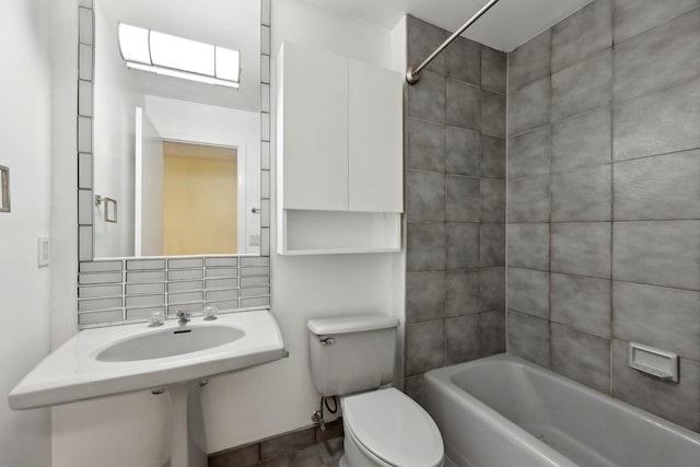 full bathroom with decorative backsplash, tiled shower / bath combo, toilet, and sink