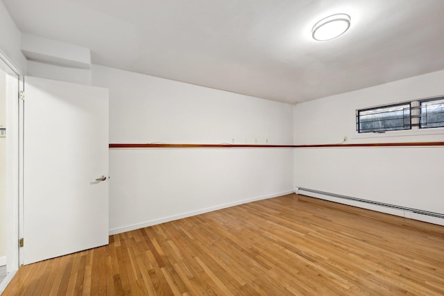 unfurnished room with baseboard heating and hardwood / wood-style floors