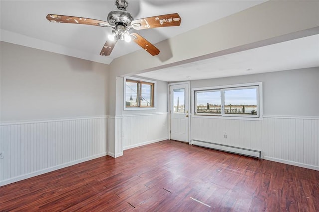 empty room with hardwood / wood-style floors, ceiling fan, and a baseboard radiator