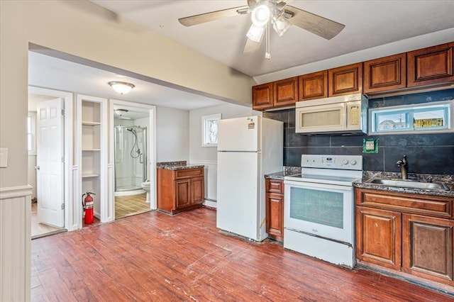 kitchen featuring backsplash, white appliances, ceiling fan, dark wood-type flooring, and sink