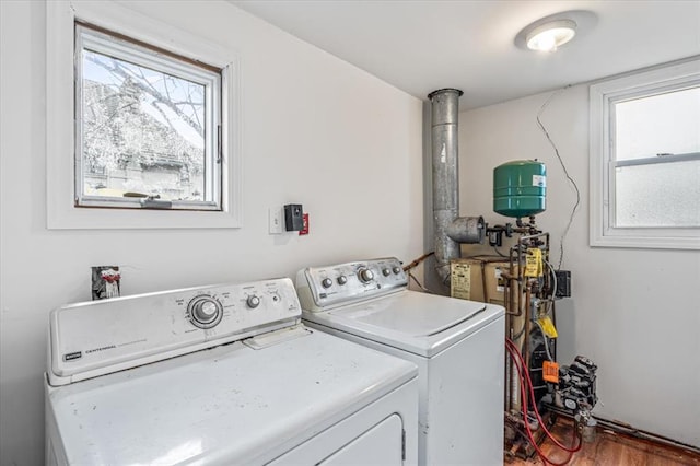 clothes washing area with washing machine and clothes dryer, plenty of natural light, and wood-type flooring