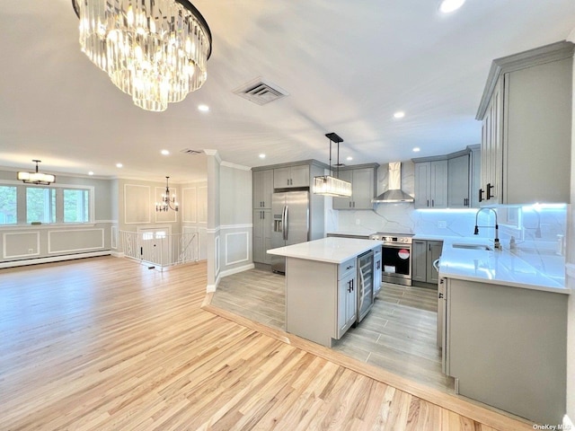 kitchen featuring stainless steel appliances, wall chimney range hood, sink, light hardwood / wood-style floors, and a kitchen island