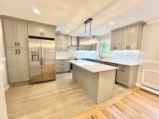 kitchen with a center island, sink, wall chimney exhaust hood, stainless steel appliances, and pendant lighting