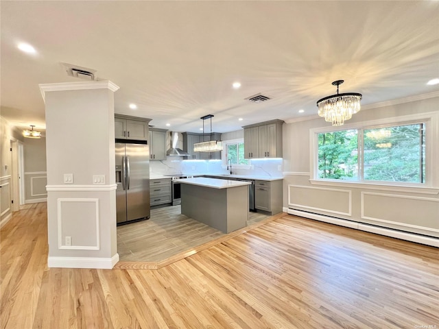 kitchen featuring gray cabinets, wall chimney range hood, hanging light fixtures, and appliances with stainless steel finishes