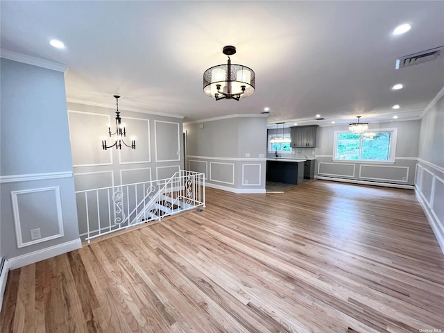 interior space with hardwood / wood-style floors, ornamental molding, baseboard heating, and a chandelier