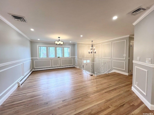 spare room with ornamental molding, an inviting chandelier, a baseboard heating unit, and hardwood / wood-style floors