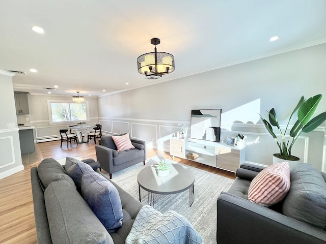 living room featuring wood-type flooring, ornamental molding, a baseboard heating unit, and an inviting chandelier