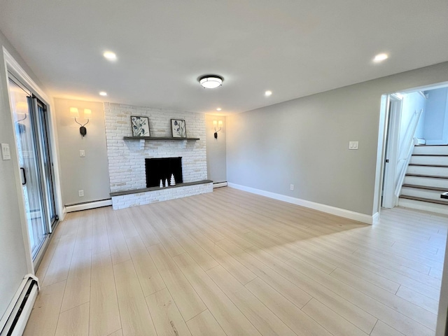 unfurnished living room with a brick fireplace, light hardwood / wood-style flooring, and a baseboard heating unit