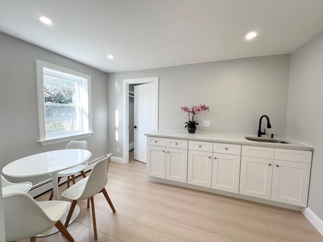 dining area featuring light hardwood / wood-style floors, sink, and a baseboard heating unit