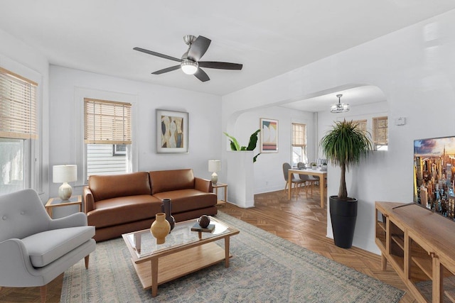 living room featuring plenty of natural light, parquet flooring, and ceiling fan with notable chandelier