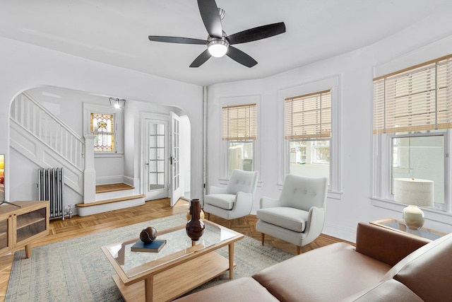 living room featuring ceiling fan, radiator heating unit, a wealth of natural light, and light parquet flooring