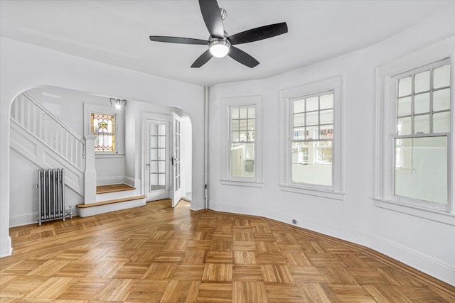 spare room featuring light parquet floors, plenty of natural light, radiator, and ceiling fan