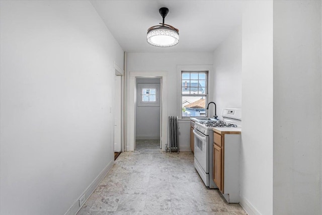 kitchen featuring radiator, white gas stove, and sink