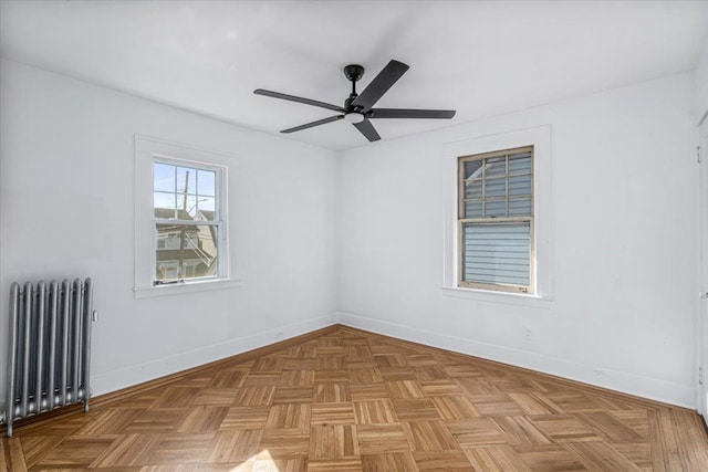 unfurnished room featuring radiator, ceiling fan, and light parquet flooring