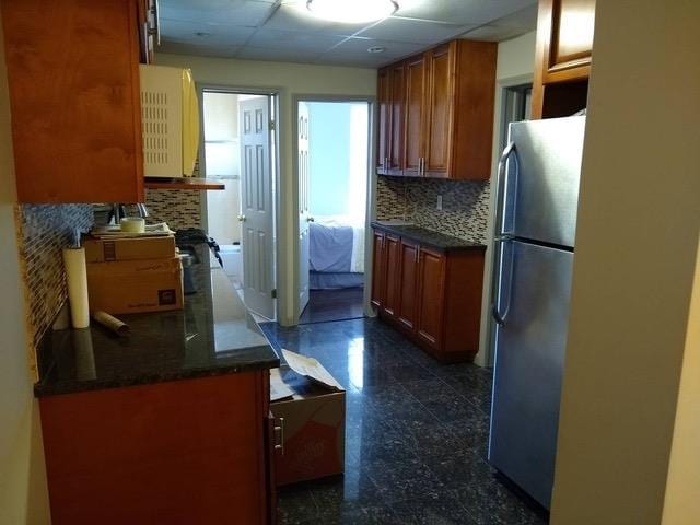 kitchen with backsplash, stainless steel refrigerator, and a paneled ceiling