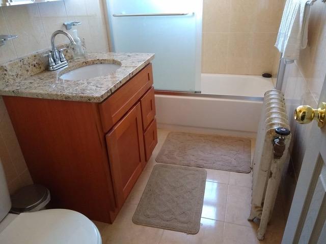 full bathroom featuring tasteful backsplash, vanity, enclosed tub / shower combo, tile patterned flooring, and toilet