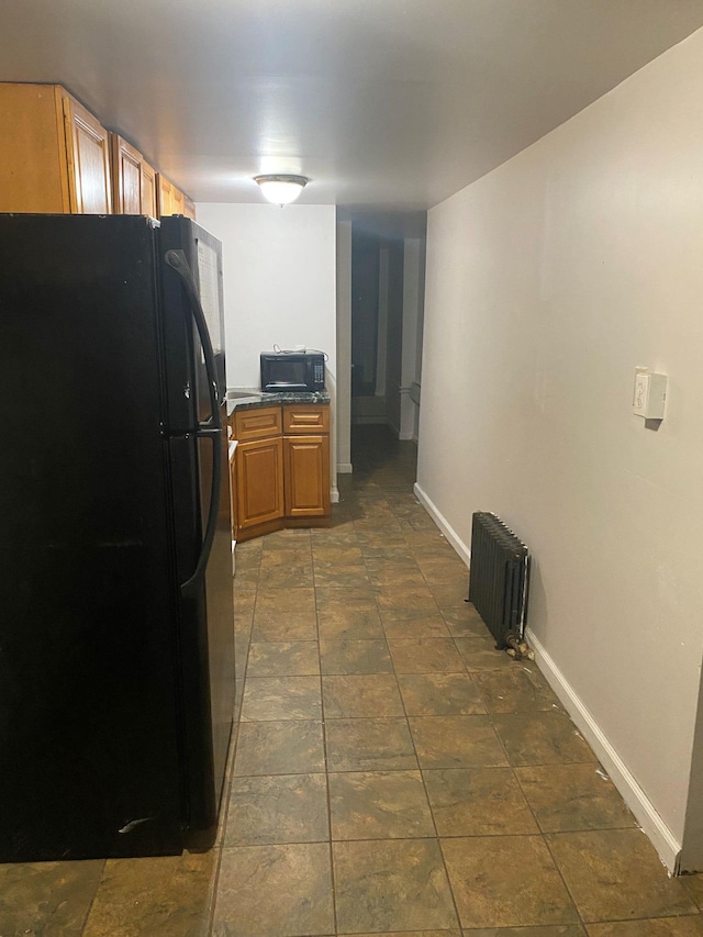 kitchen with radiator heating unit and black appliances