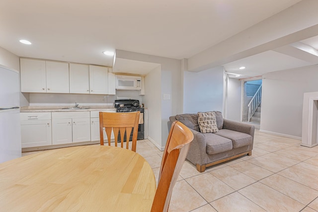 kitchen featuring white appliances, sink, light tile patterned floors, and white cabinets