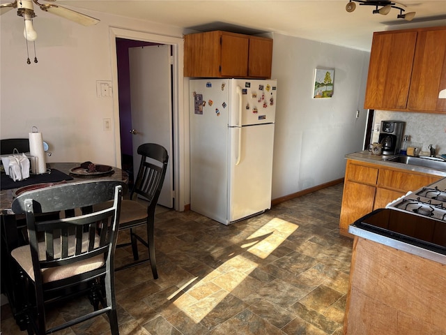 kitchen with ceiling fan, white fridge, sink, and tasteful backsplash